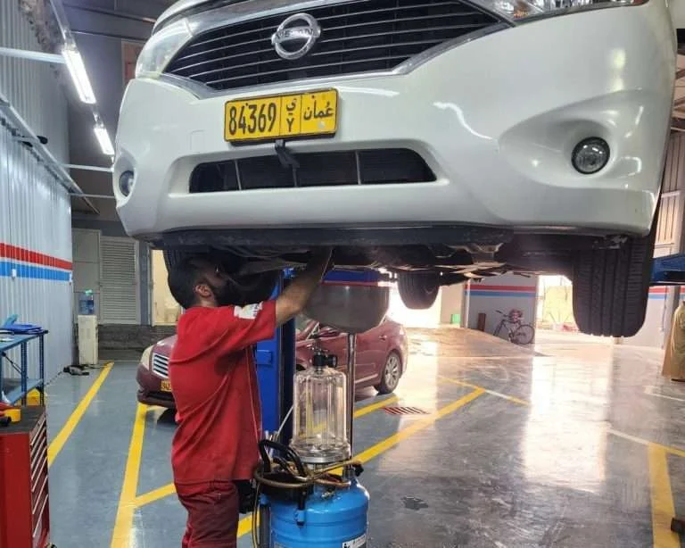 A Sial Kingdom technician inspecting the underbody of a vehicle at the Al Maabilah workshop in Muscat.