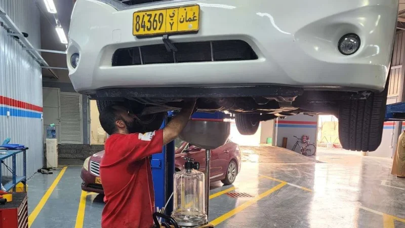 A Sial Kingdom technician inspecting the underbody of a vehicle at the Al Maabilah workshop in Muscat.